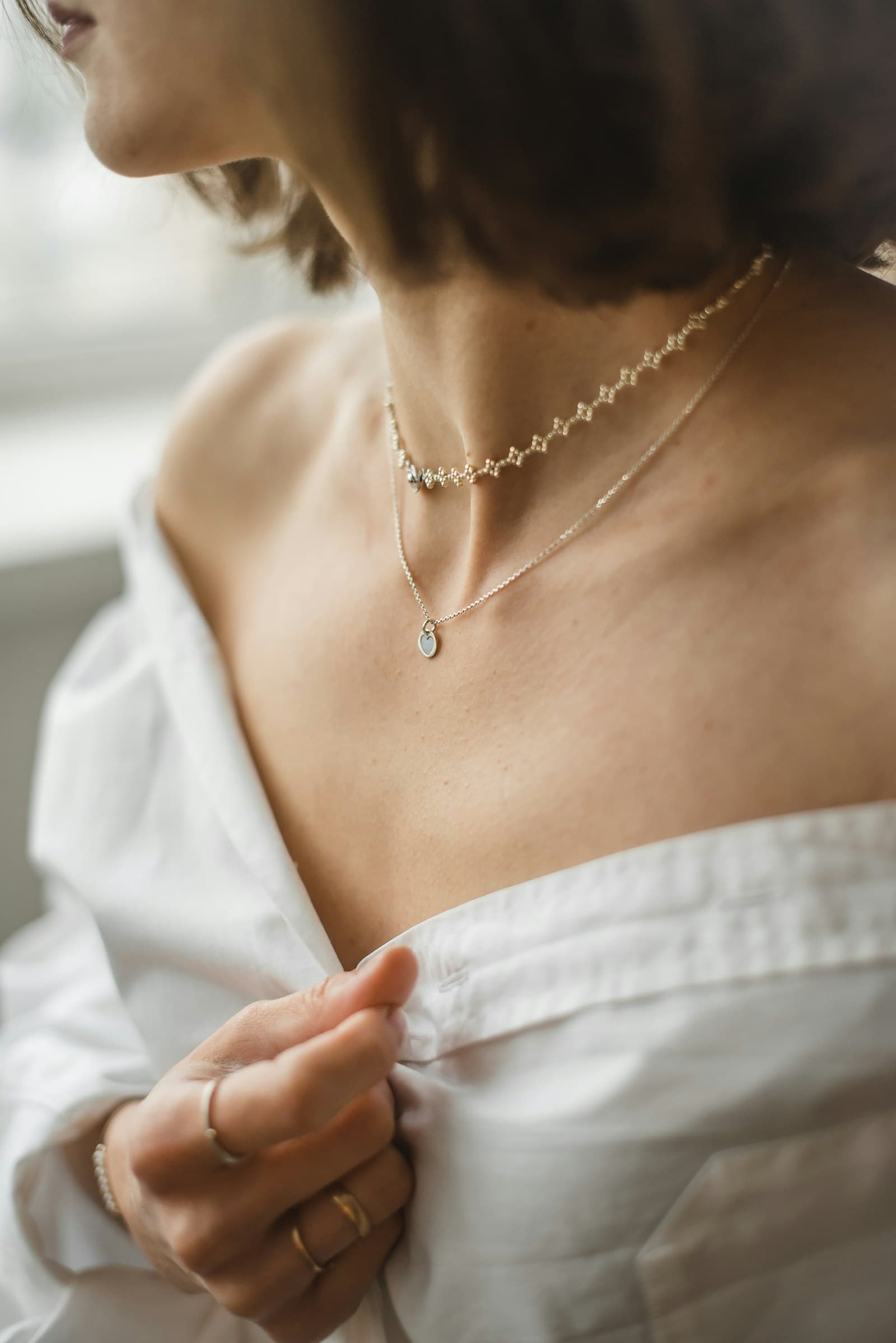Woman in an off-the-shoulder white top wearing a delicate layered necklace