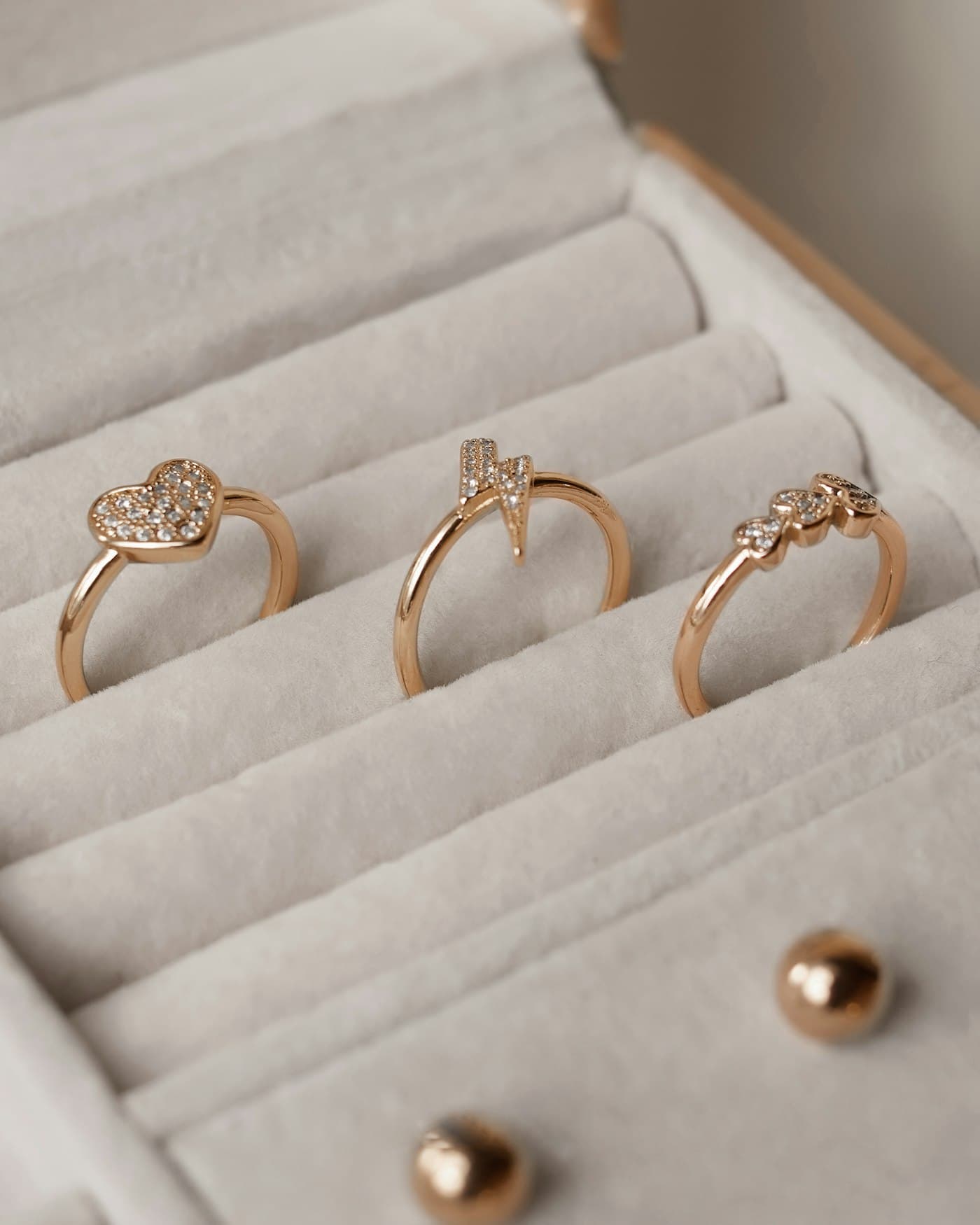Three gold rings resting in a cream jewellery box