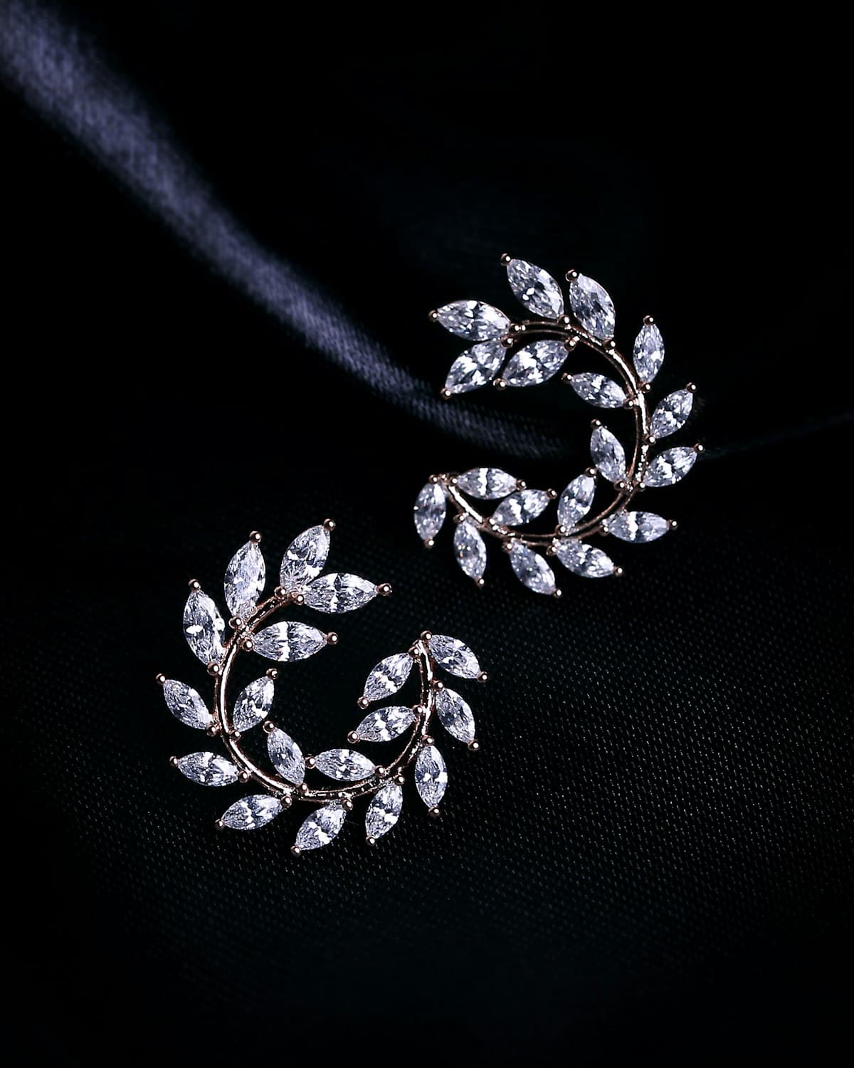 Laurel-shaped diamond earrings on black velvet