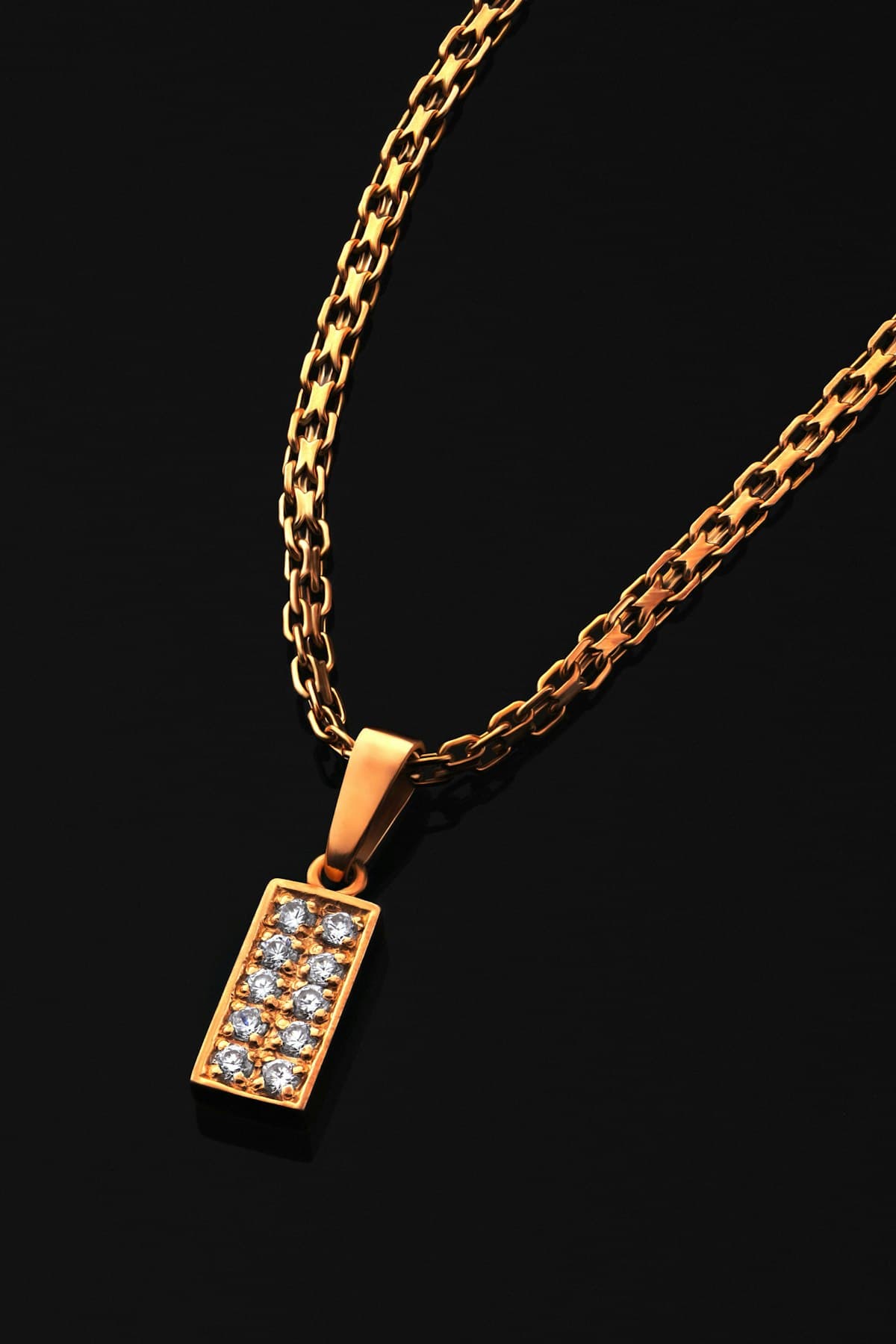 Gold necklace with a diamond pendant against a black background