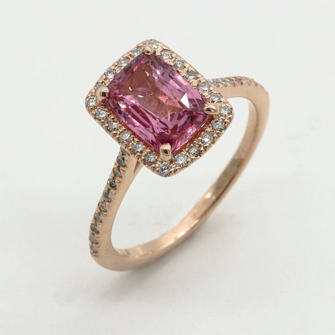 Rose gold ring with an emerald-cut pink gemstone surrounded by small diamonds