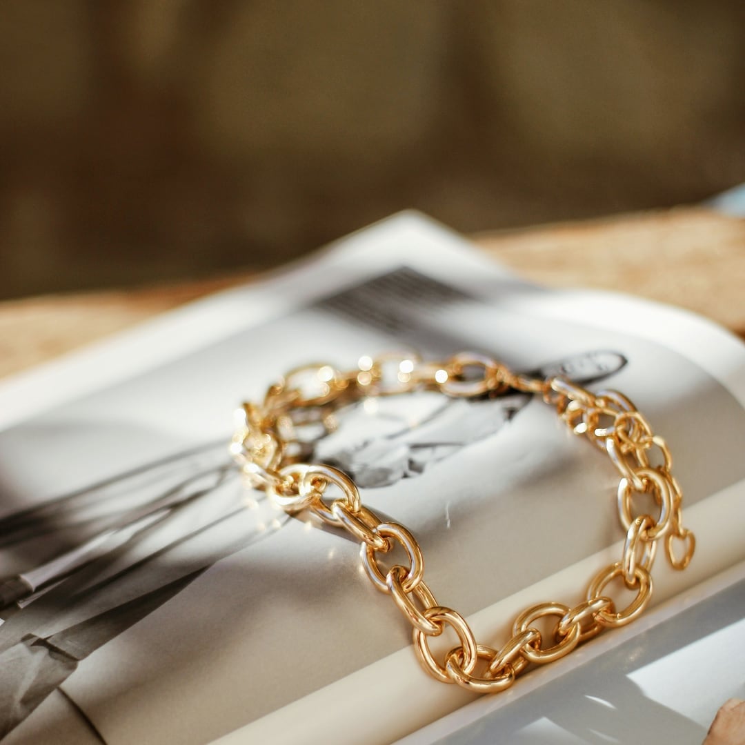 Chunky gold chain link bracelet resting on an open magazine