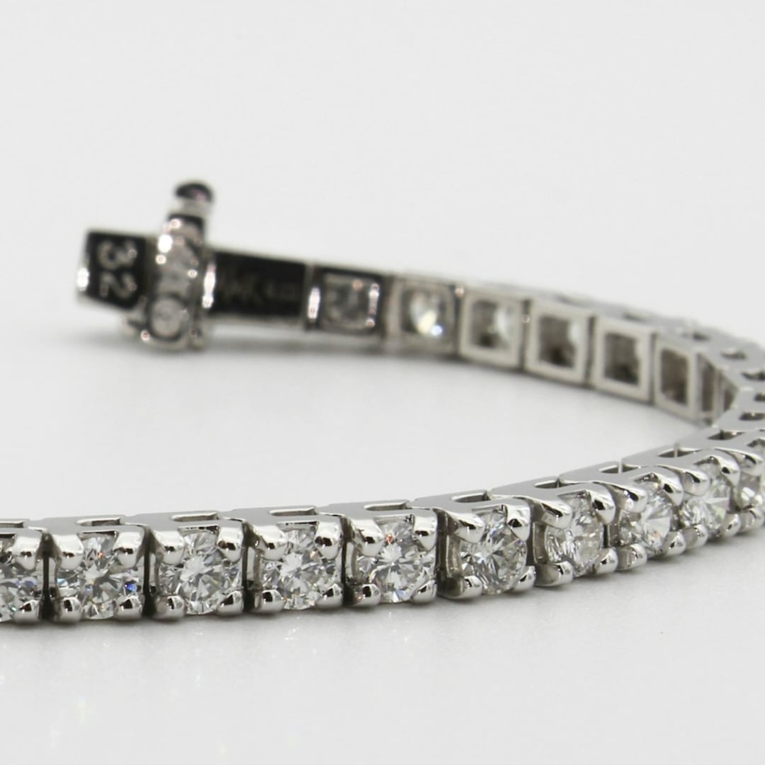 Close-up detail — diamond tennis bracelet laid flat on a pale background